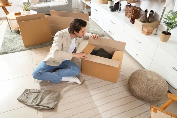 stock image Handsome young man unpacking wardrobe boxes with stylish clothes in dressing room