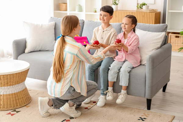 Маленькие дети забирают яблоки у матери дома