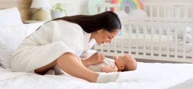 Bornozlu mutlu kadın evde bebeğiyle oynuyor.