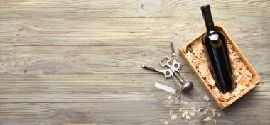 Şarap şişesi, tirbuşon ve cam dolu bir kutu ahşap arka planda mesaj için yer var.