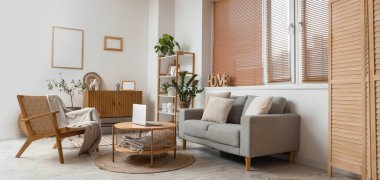 Gri kanepesi, koltuğu ve masası olan modern oturma odasının içinde.