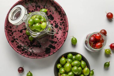 Beyaz arka planda taze bektaşi üzümlü kase ve kavanozlar.