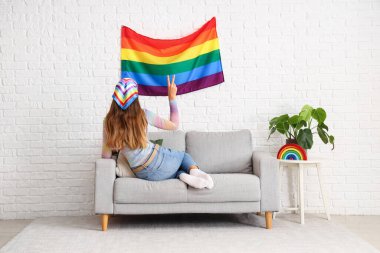 Kanepede LGBT bayrağı taşıyan genç bir kadın.