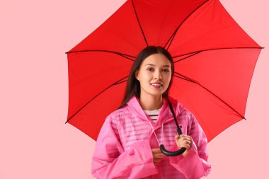 Pembe arka planda şemsiyesi olan Asyalı güzel bir kadın.