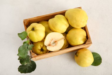 Tahta kutu, tatlı olgun ayva ve beyaz arka planda yapraklar.