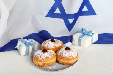 Lezzetli çörekler ve Hanuka kutlaması için İsrail bayrağına karşı ışıklı masada hediyeler.