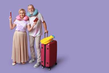 Seyahat aksesuarları ve eflatun çantalı olgun bir çift.