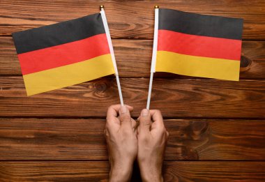 Ahşap arka planda Almanya bayrakları olan erkek eller