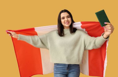 Sarı arka planda Kanada bayrağı ve pasaportu olan güzel, mutlu bir kadın.