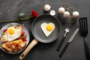 Lezzetli kızarmış yumurta, kruvasan, tabakta domates ve arka planda gül çiçeği karışımı.