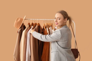 Bej arka planda elbise askısı olan kadın stilisti