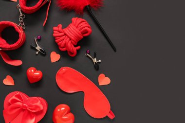 Farklı seks oyuncaklarıyla kompozisyon ve karanlık arka planda kağıt kalpler. Sevgililer Günü kutlaması