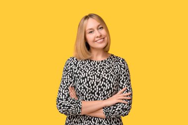 Sarı arka planda kısa saçlı mutlu genç bir kadın.