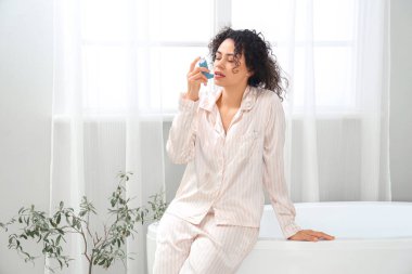 Genç Afro-Amerikalı kadın, astım spreyi kullanıyor.