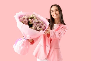 Pembe arka planda güzel güllerle dolu buketi olan mutlu genç bir kadın.