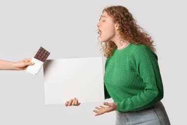 Gri arka planda çikolata çubuğu olan boş bir poster ve el tutan güzel genç bir kadın.
