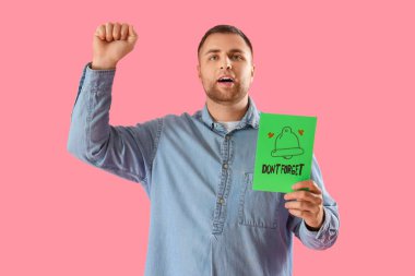 Elinde kağıt olan genç adam Pembe arka planda çan çizmeyi unutma