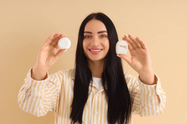 Bej arka planda farklı diş ipleri olan güzel, mutlu genç bir kadın.