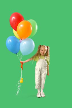 Yeşil arka planda renkli balonları olan mutlu küçük kız.