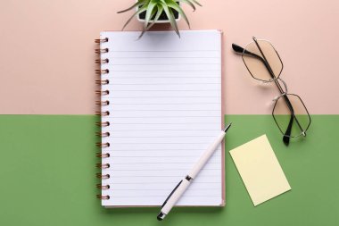 Renk arkaplanı üzerine kalem, gözlük ve defter