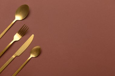 Kahverengi arka planda temiz altın çatal bıçak takımı