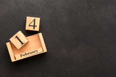 Siyah arka planda 14 Şubat tarihli ahşap küp takvimi. Üst görünüm