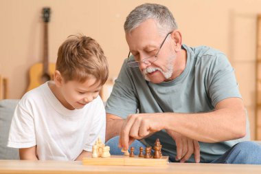 Büyükbaba ve küçük tatlı torunu evde satranç oynuyorlar.