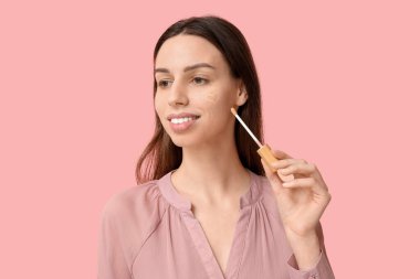 Pembe arka planda, kalp şeklinde güzel bir genç kadın.