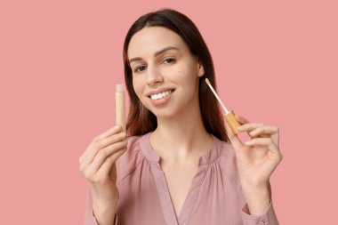 Pembe arka planda, kalp şeklinde güzel bir genç kadın.