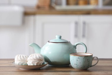 Çaydanlık, bir fincan sıcak çay ve mutfak masasında zephyr.