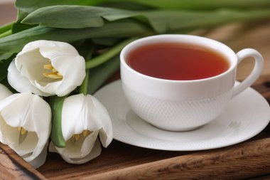 Sıcak demlenmiş çay tepsisi ve laleler, yakın plan.