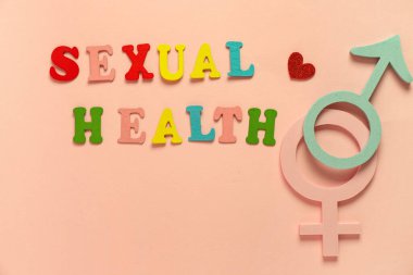 Pembe arka planda cinsiyetçi sağlık, erkek ve kadın sembolleri içeren renkli harfler.