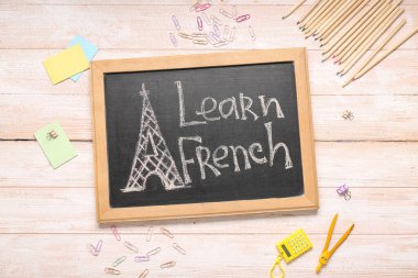 Metin LeARN FRENCH ve hafif ahşap zemin üzerinde farklı kırtasiye malzemesi içeren tebeşir tahtası