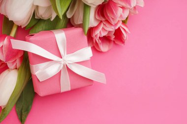 Hediye kutusu ve pembe arka planda güzel laleler.