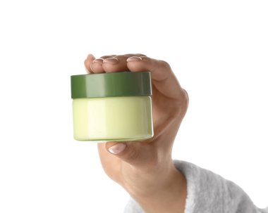 Beyaz arka planda krema kavanozu olan kadın eli, yakın plan.