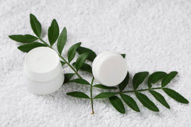 Hafif kumaş arka planında krema ve bitki yaprakları olan kompozisyon