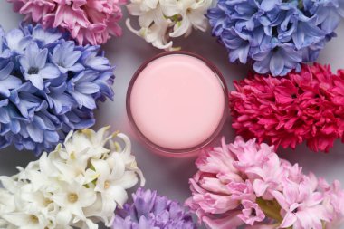 Krema kavanozlu kompozisyon ve gri arka planda güzel sümbül çiçekleri.