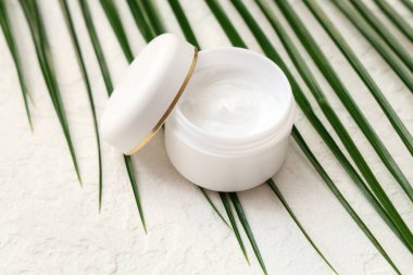 Hafif arka planda doğal krema ve palmiye yaprağı kavanozu