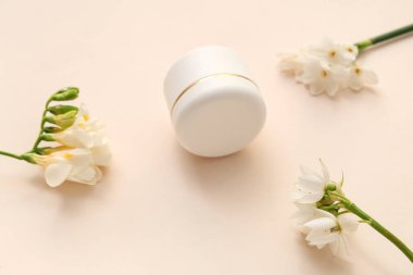 Renkli arkaplanda krema kavanozu ve frezya çiçekleri olan kompozisyon