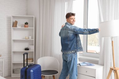 Otel odasında perdeleri açan erkek turist