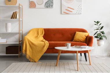 Kırmızı kanepesi, masası ve raf ünitesi olan şık bir oturma odası.