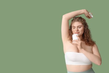 Yeşil arka planda deodorantı olan güzel genç bir kadın.