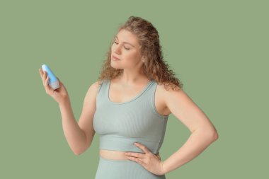 Yeşil arka planda deodorantı olan güzel genç bir kadın.