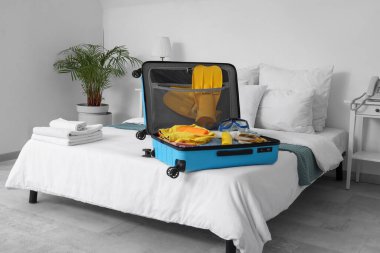 Yatağında bavul olan bir otel odası.