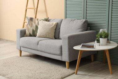 Gri kanepeli, masalı ve katlanır perdeli oturma odasının içi.