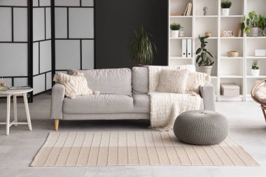 Kanepesi, raf ünitesi ve bitkileri olan şık bir oturma odası.