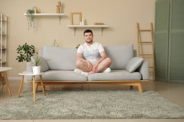 Oturma odasında kanepede oturan genç adam