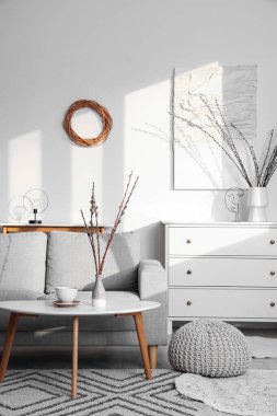 Kanepe, masa ve vazolarda söğüt dallarıyla aydınlık oturma odasının içinde.