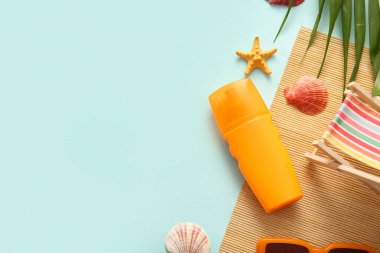 Bir şişe güneş kremi, güverte sandalyesi ve arka planda palmiye yaprakları.