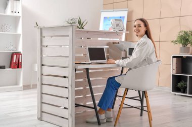 Klinikteki masada oturan kadın resepsiyonist.